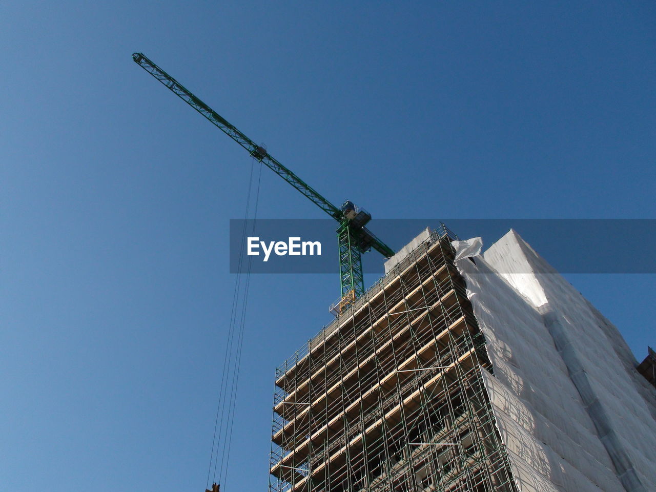 LOW ANGLE VIEW OF CRANES AGAINST BUILDING