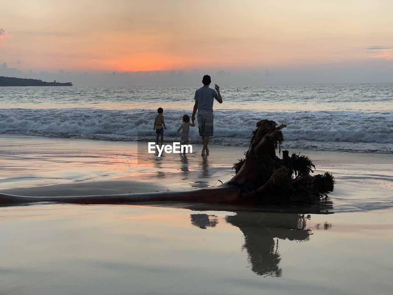 Men on beach against sky during sunset