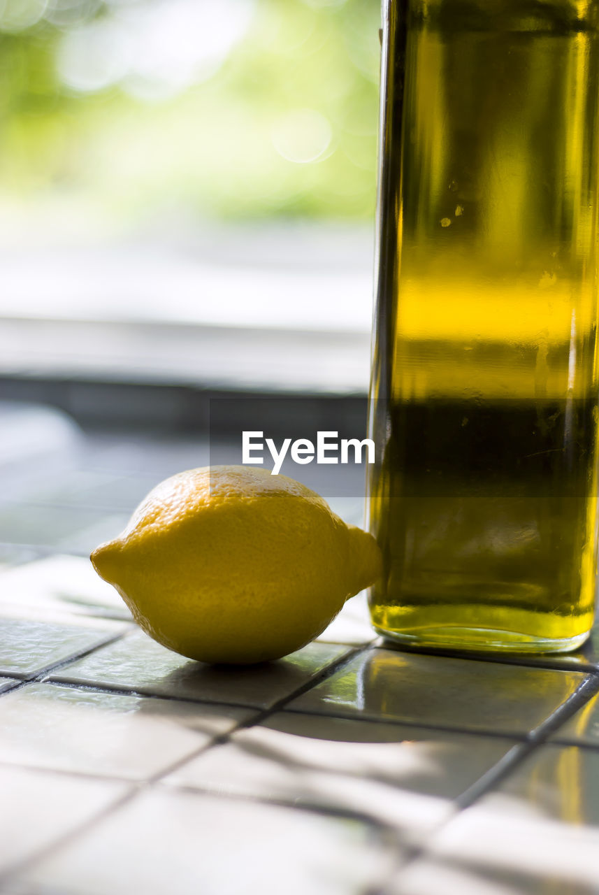 Close-up of lemon by glass bottle on table
