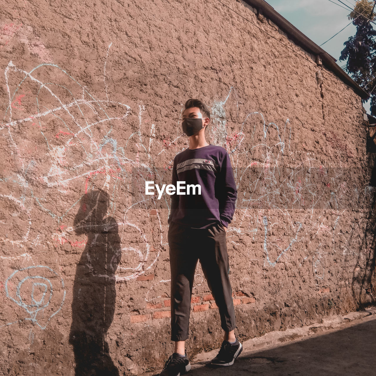 MAN STANDING AGAINST WALL