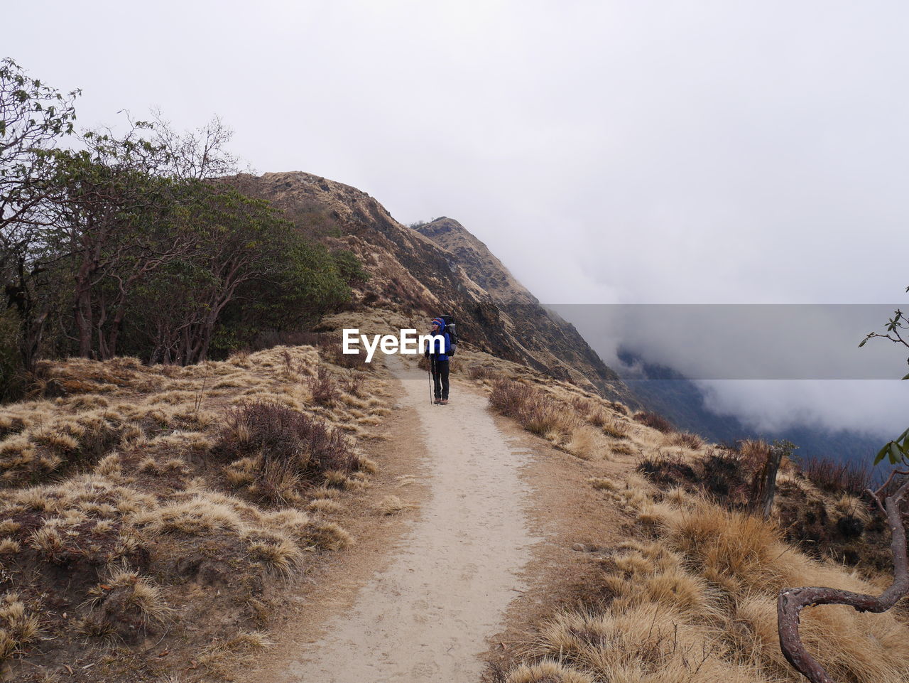 REAR VIEW OF MAN WALKING ON MOUNTAIN