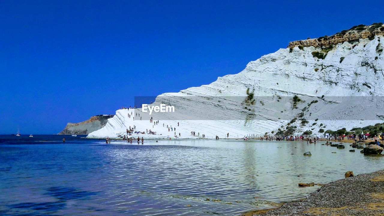 SCENIC VIEW OF SEA AND MOUNTAIN AGAINST CLEAR BLUE SKY