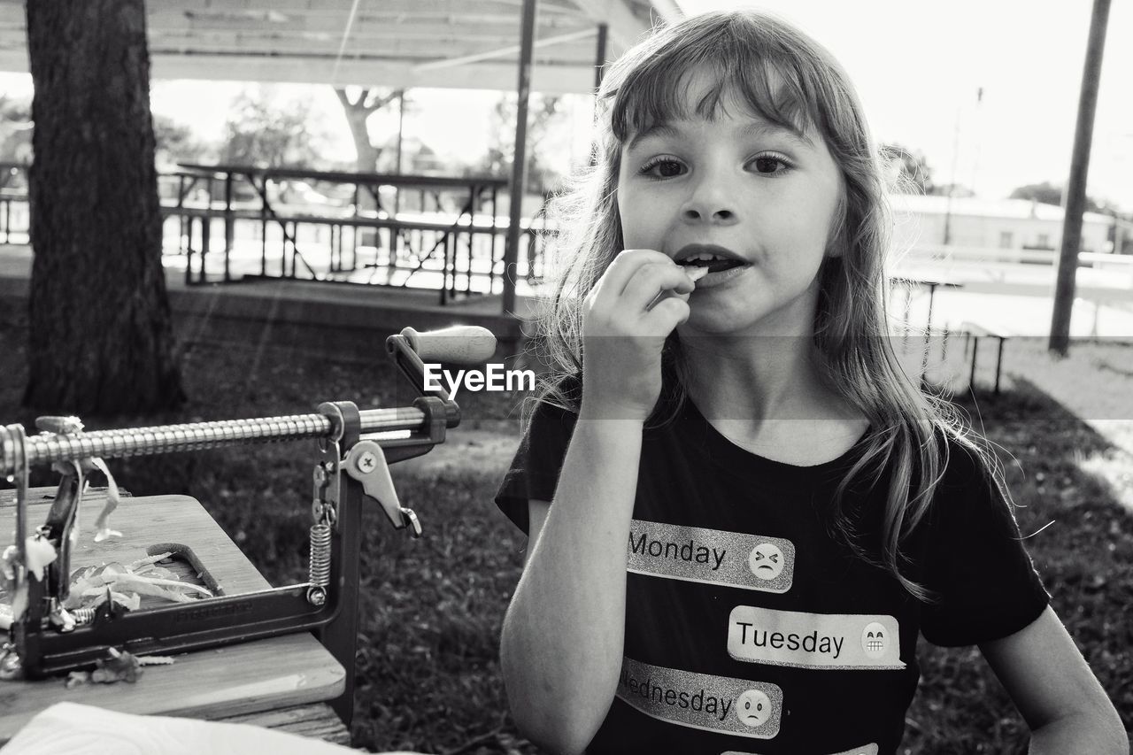 Portrait of girl eating food while standing outdoors