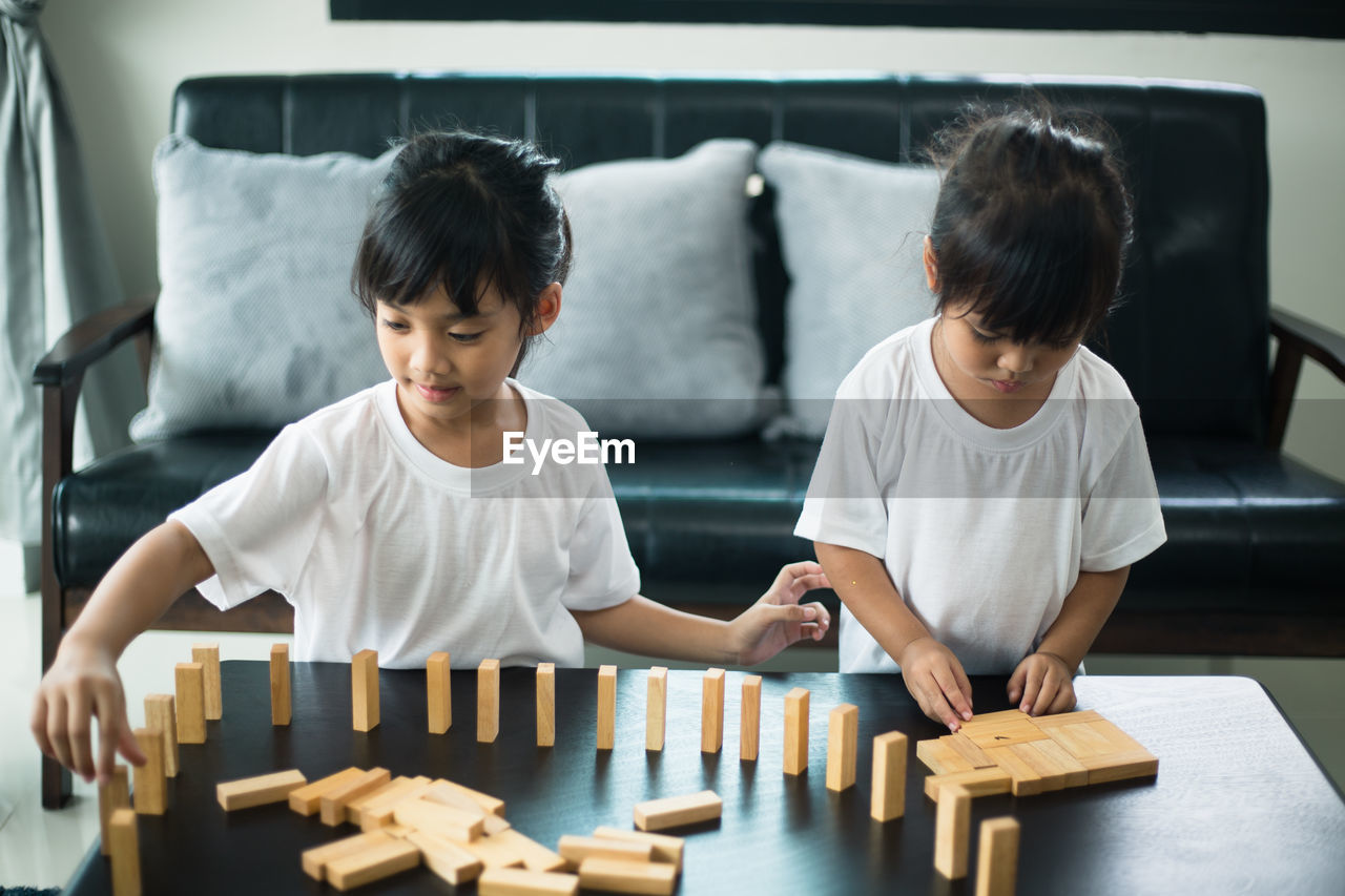 Siblings playing with toy blocks on table