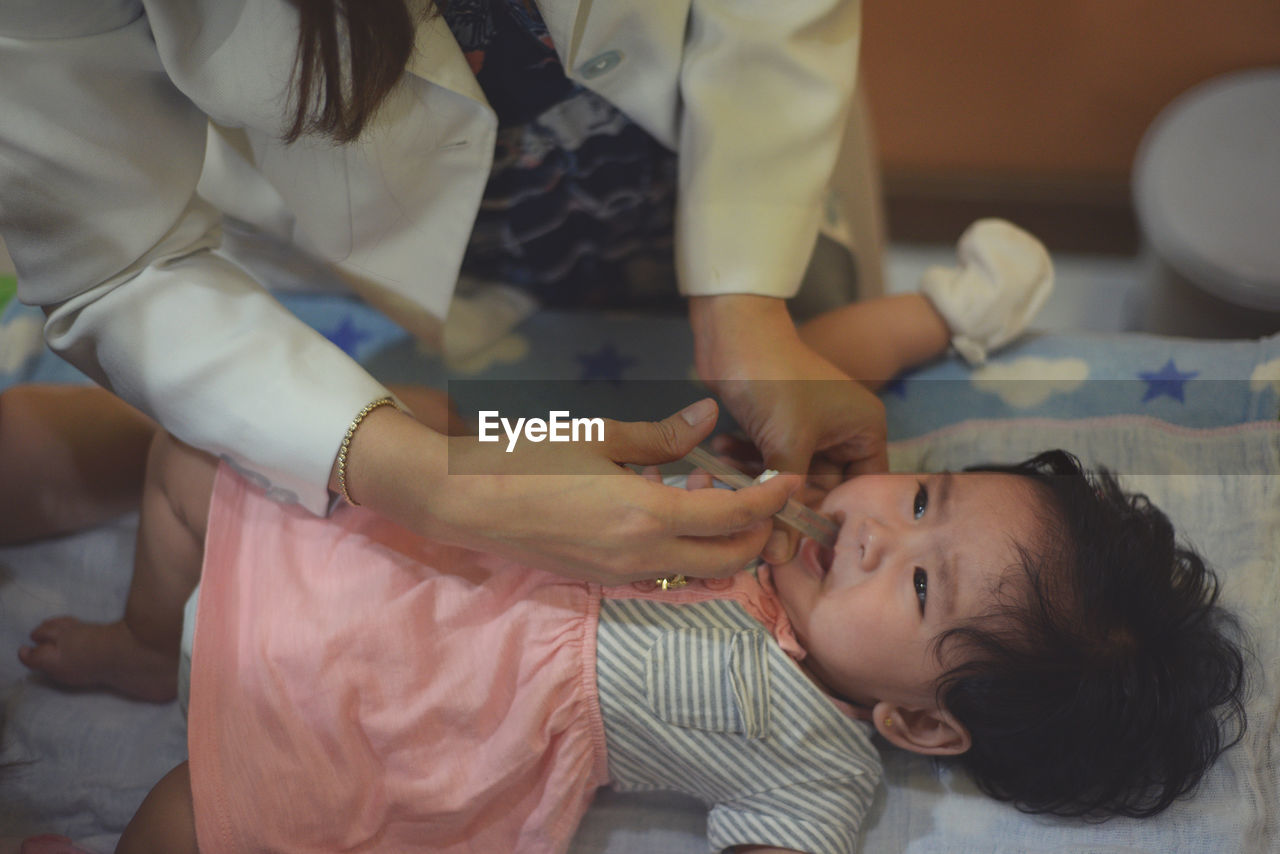 Midsection of doctor examining baby girl