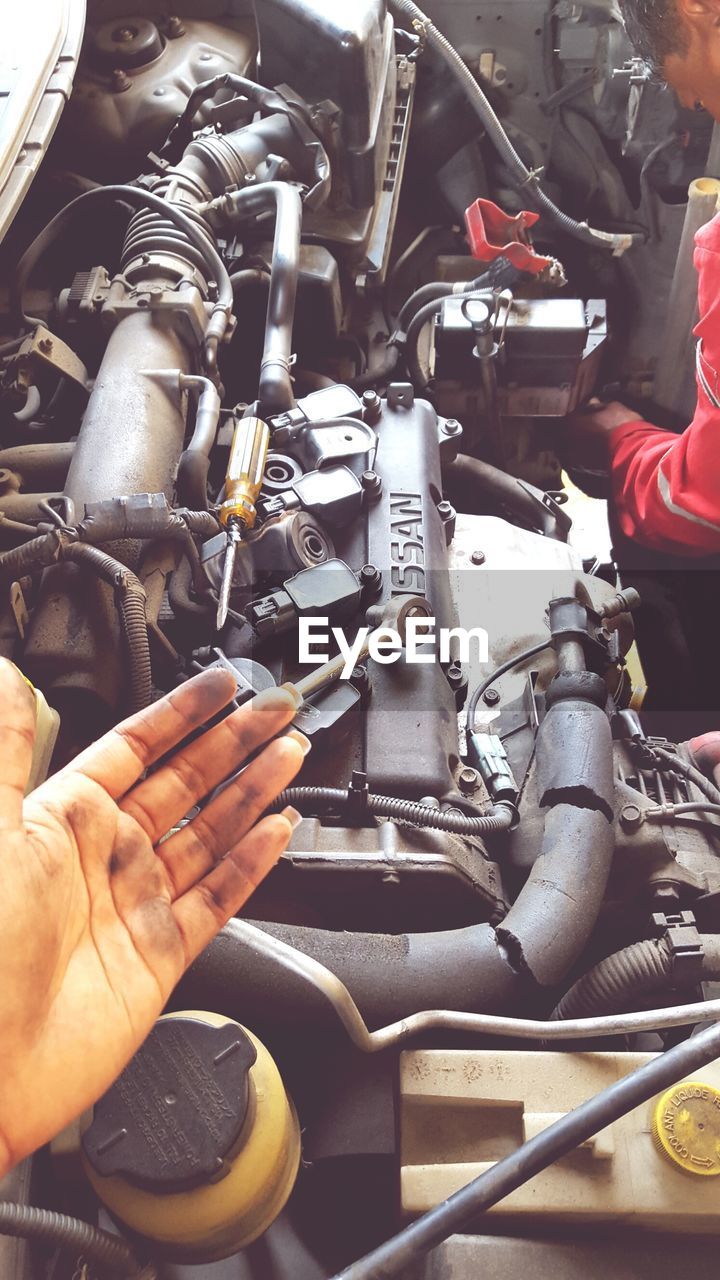 Cropped hand of mechanic by car engine