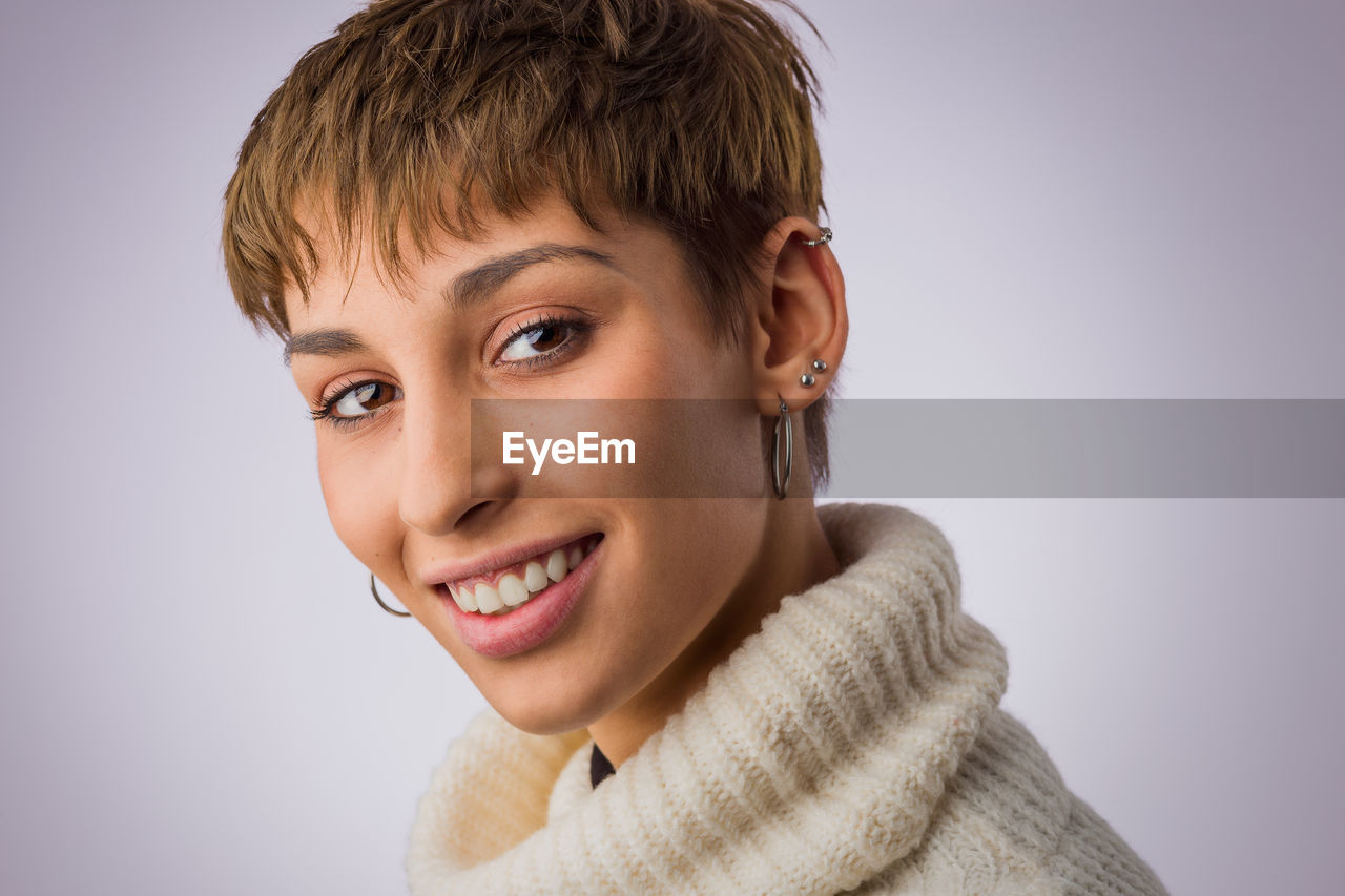 Close-up portrait of young woman against colored background