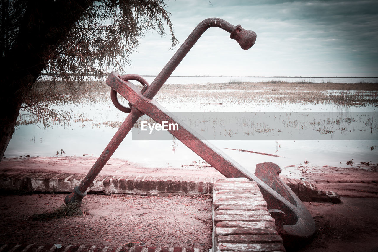 Close-up of metal structure on beach against sky