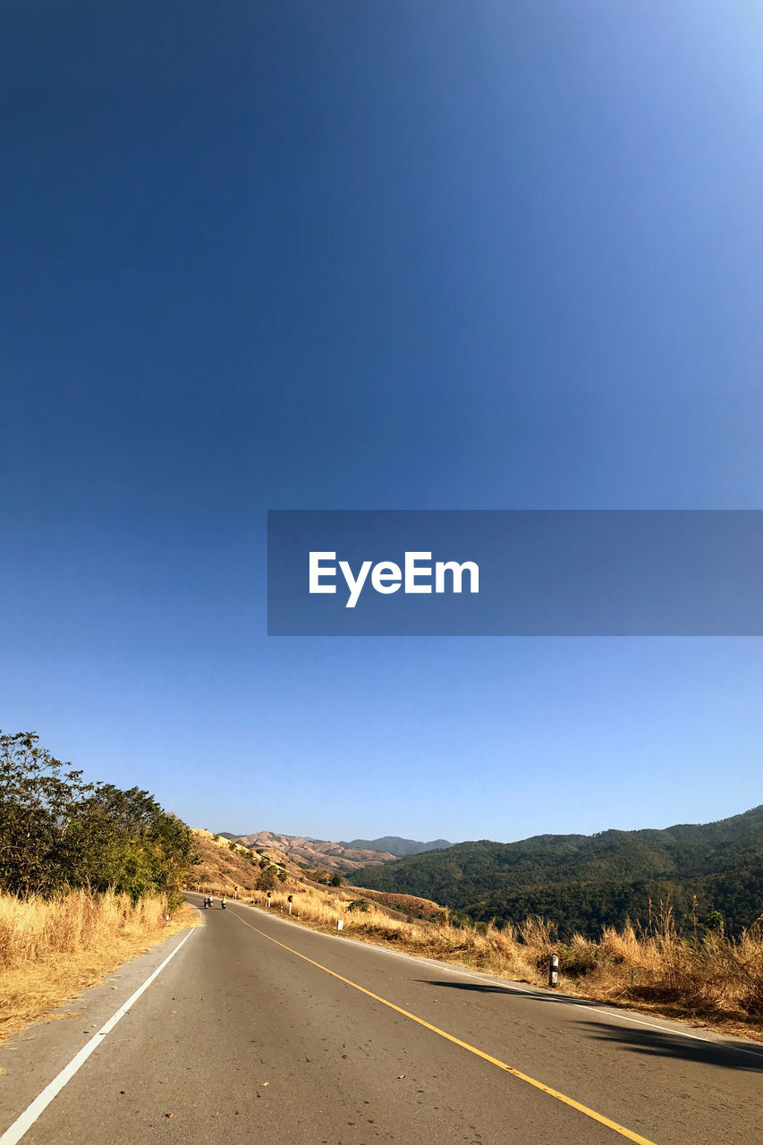 EMPTY ROAD AMIDST LANDSCAPE AGAINST CLEAR BLUE SKY