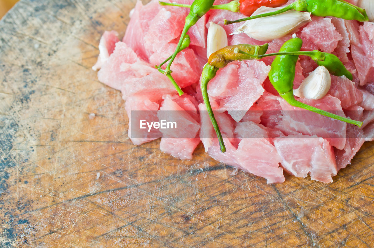 Close-up of pork with chili pepper and garlic clove on cutting board