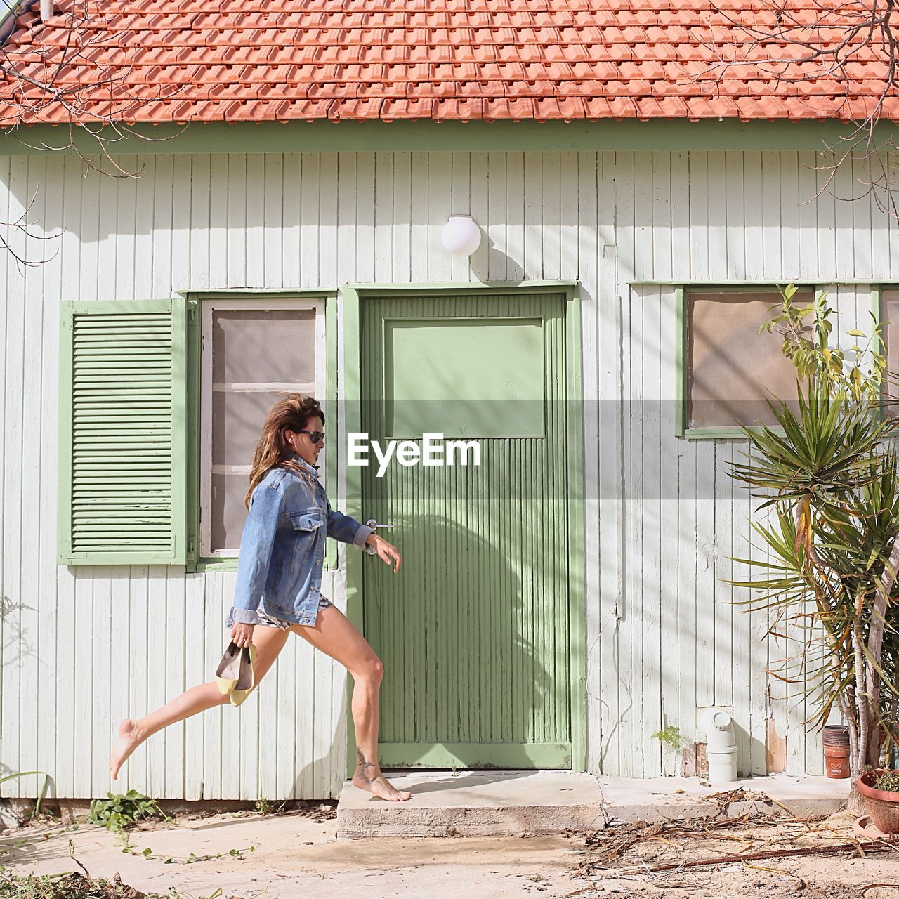 Side view of woman walking against house