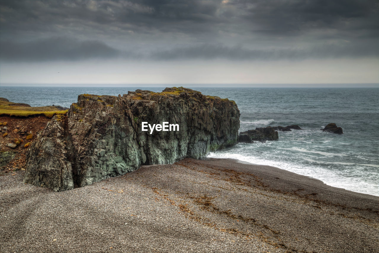 sea, rock, water, beach, land, sky, ocean, shore, cloud, horizon, coast, beauty in nature, scenics - nature, wave, horizon over water, sand, nature, body of water, cliff, tranquility, tranquil scene, terrain, coastline, no people, seascape, motion, outdoors, wind wave, overcast, idyllic, environment, storm, bay, non-urban scene, rock formation, day, travel destinations, storm cloud, dramatic sky