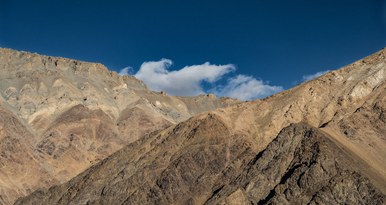 Low angle view of rocky mountains against blue sky