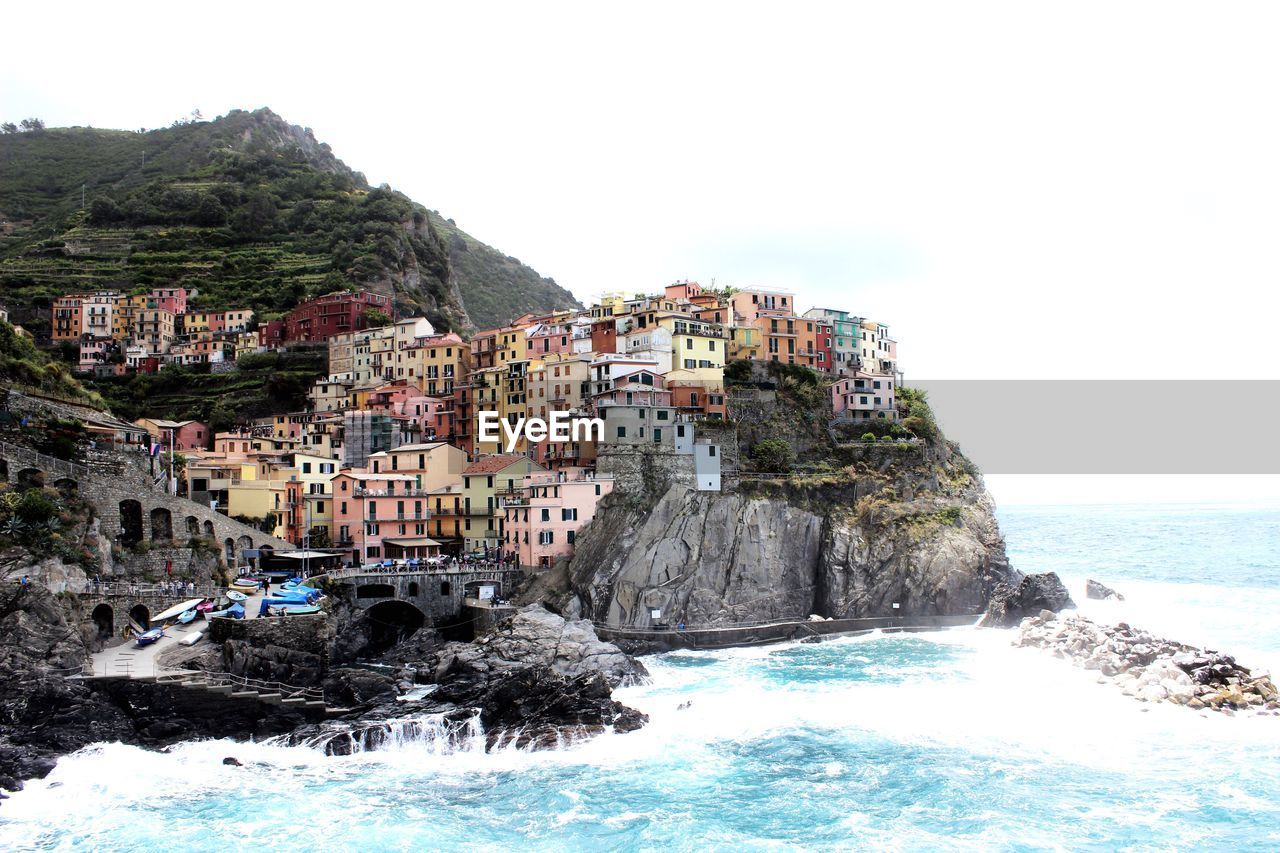 SCENIC VIEW OF SEA BY MOUNTAIN AGAINST CLEAR SKY