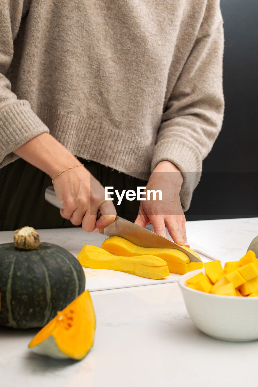 midsection of man holding pumpkin on table