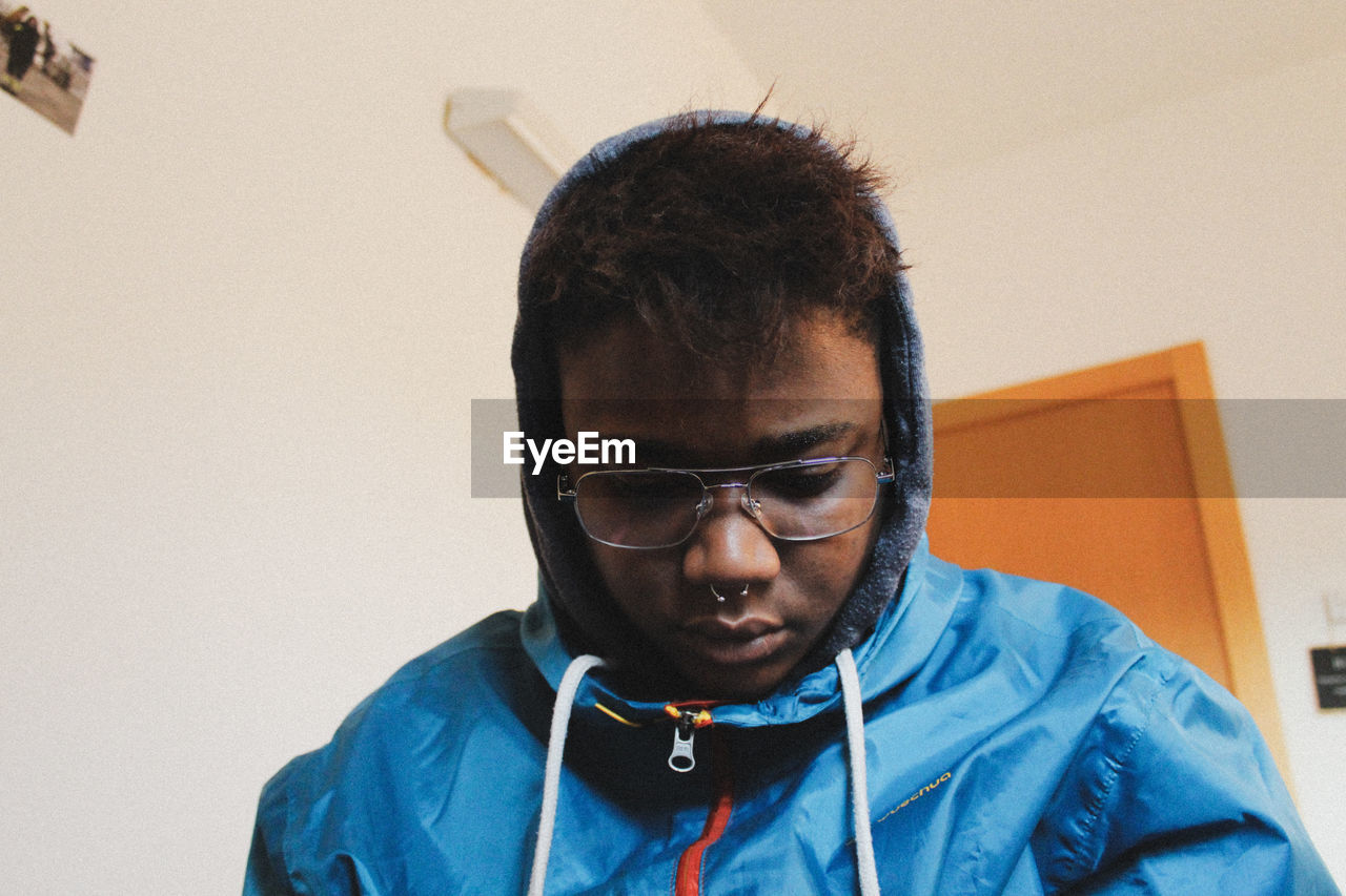 PORTRAIT OF YOUNG MAN WITH EYEGLASSES AT HOME