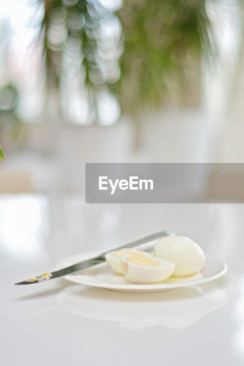 Boiled eggs on a kitchen table, healthy protein rich breakfast. plate, a knife, white background.