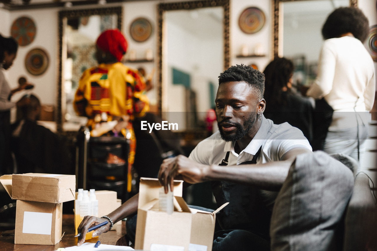 Male hair expert packing beauty product in box at barber shop