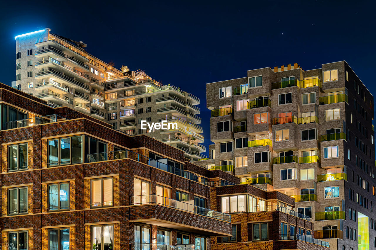 Low angle view of illuminated buildings against sky at night