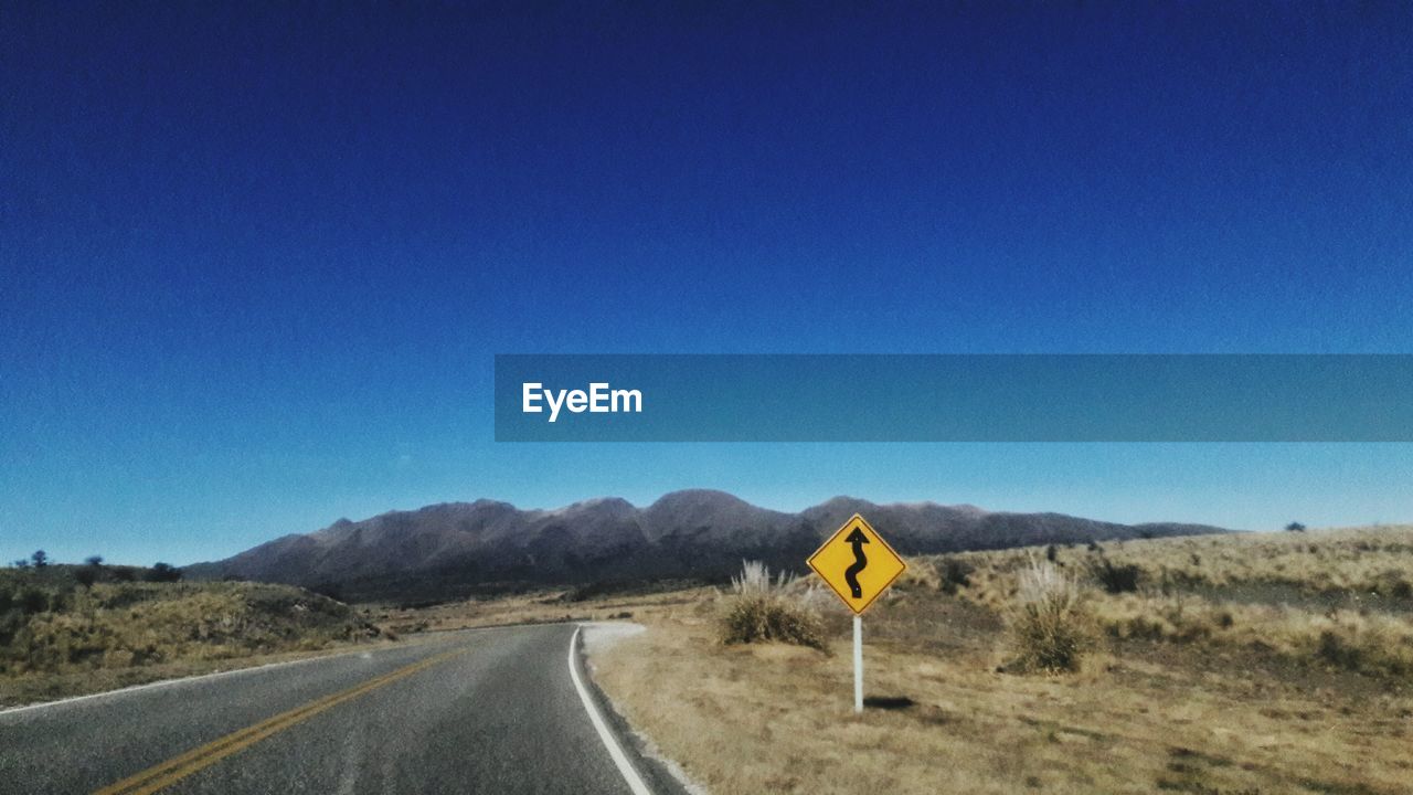 Road passing through landscape against blue sky