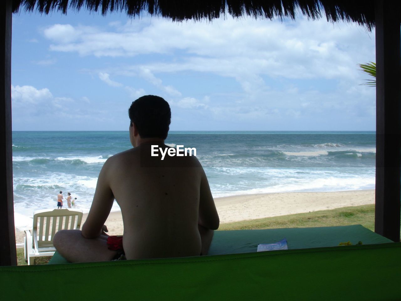 Rear view of men sitting against sea