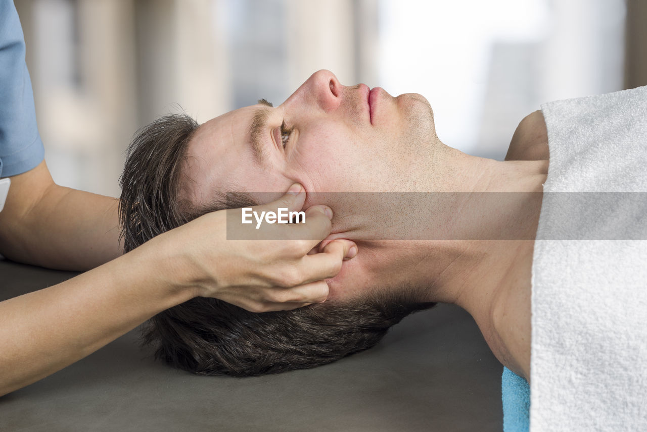 Cropped image of masseur massaging man in spa