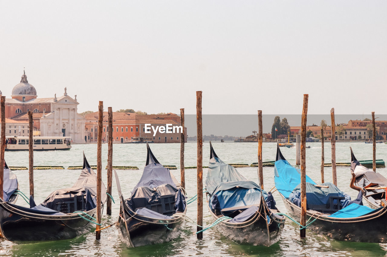 BOATS MOORED IN CANAL WITH BUILDINGS IN BACKGROUND