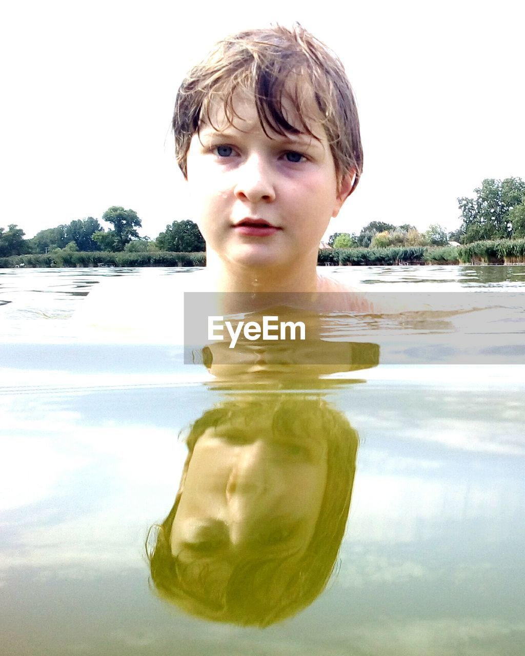 Boy swimming in lake against sky