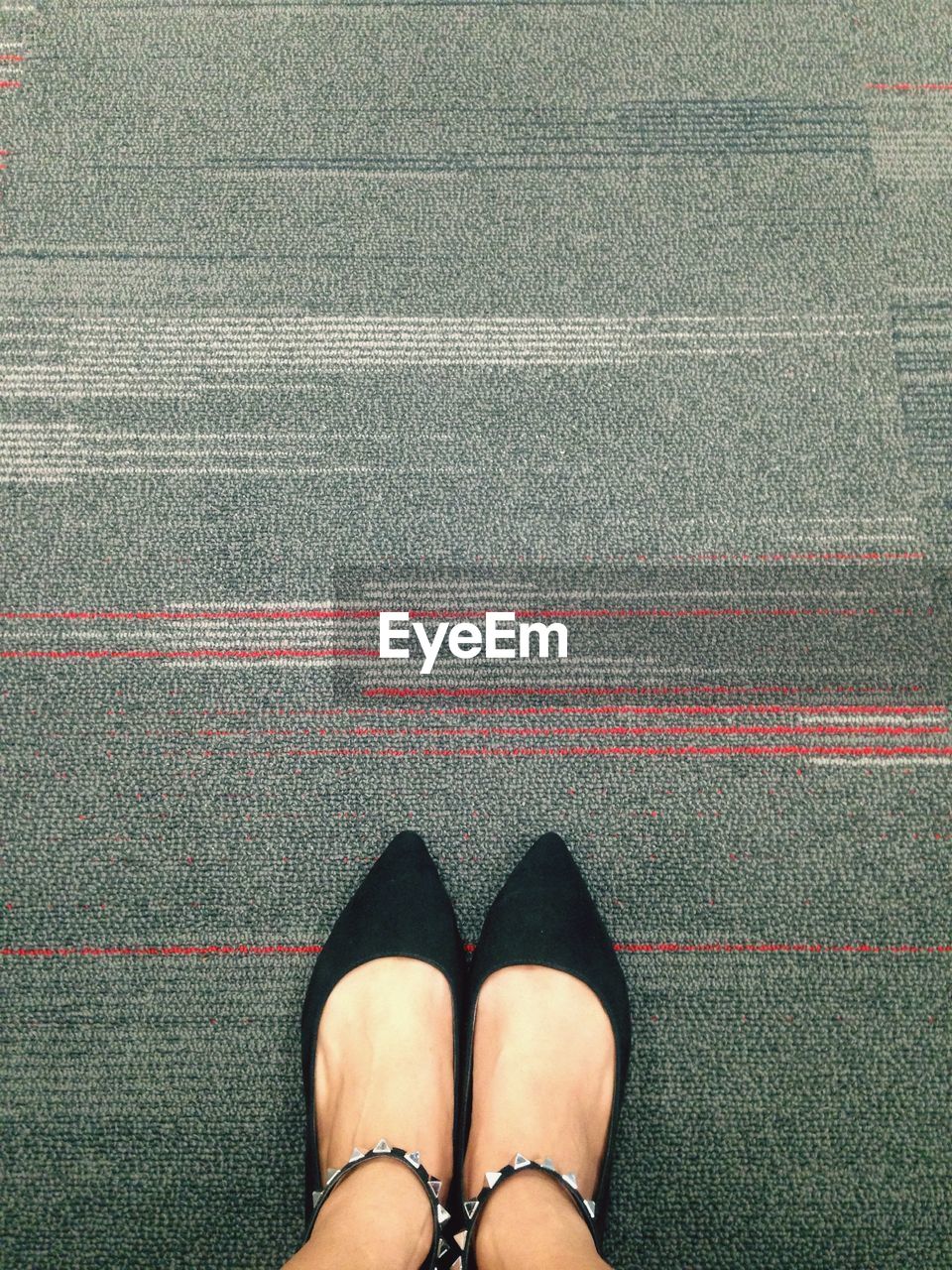 Low section of woman standing on gray carpet