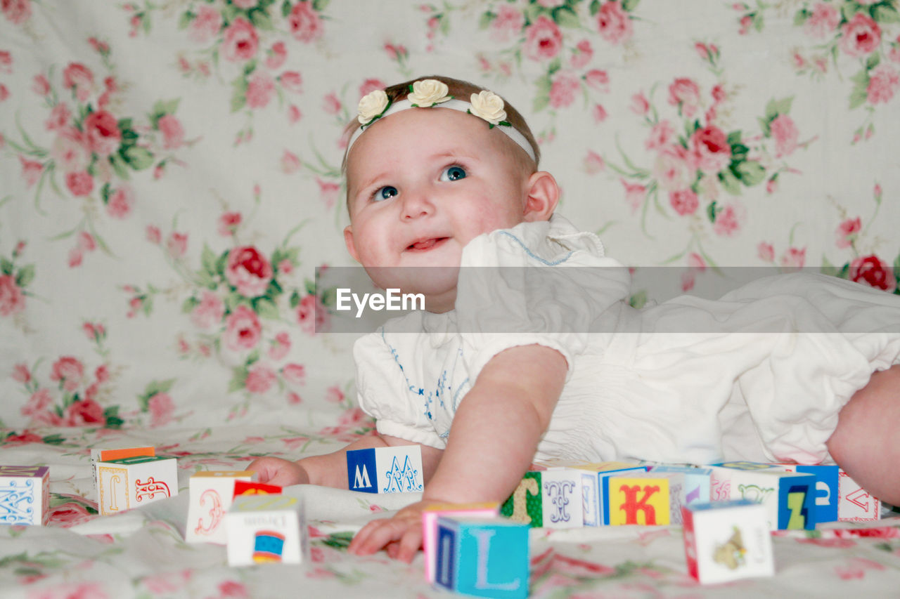 Portrait of cute baby sitting on bed at home