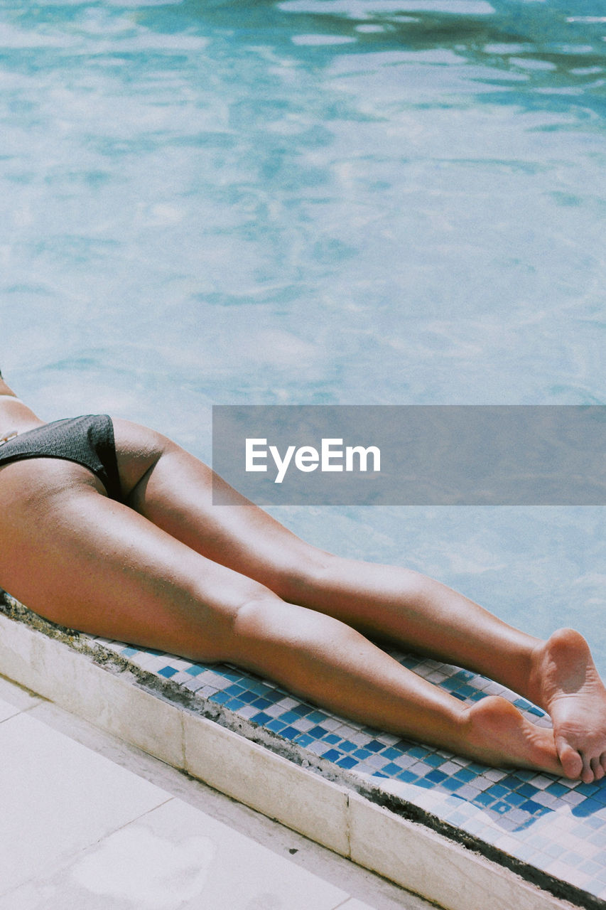 Low section of woman relaxing in swimming pool