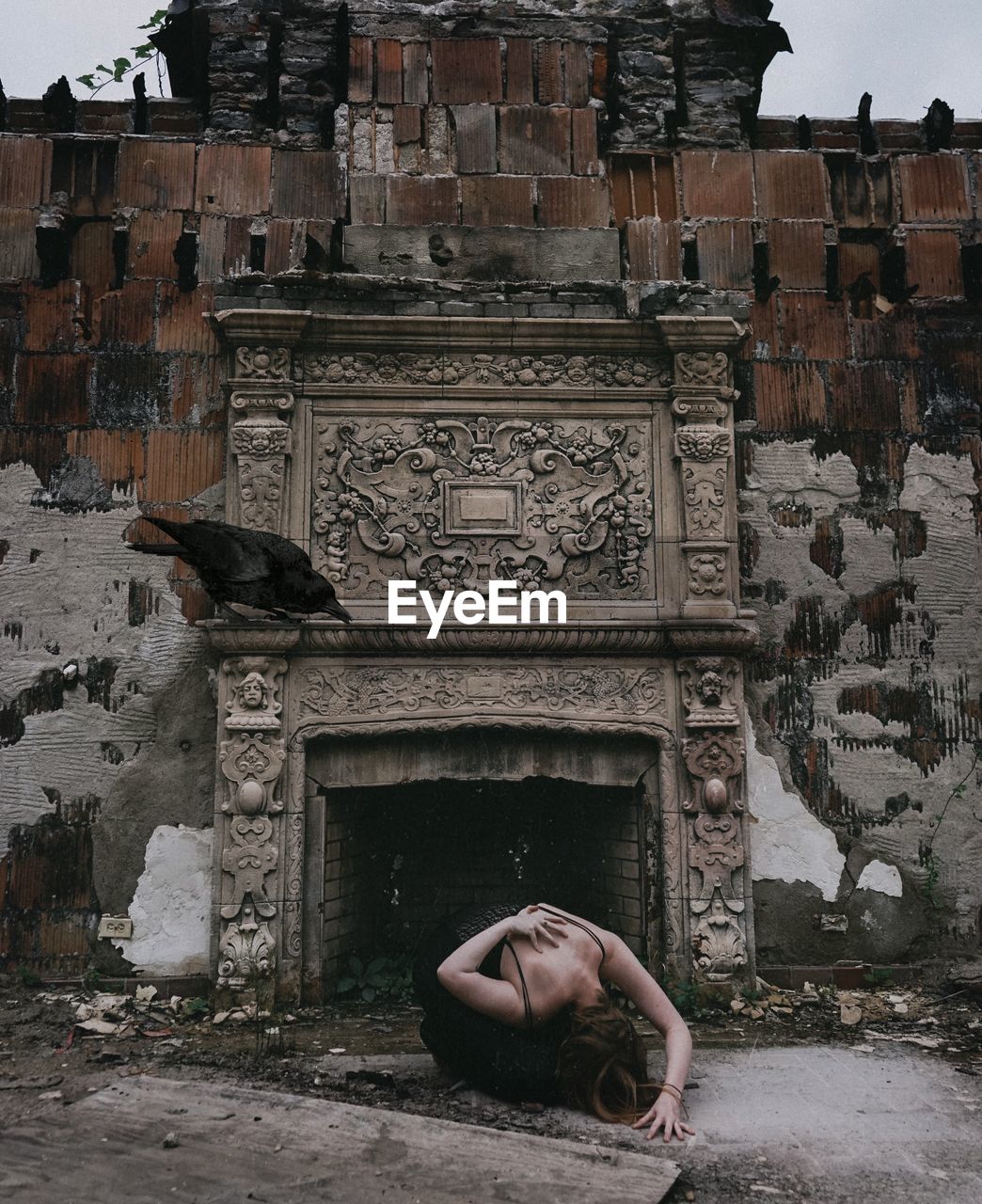 Woman bending against abandoned building