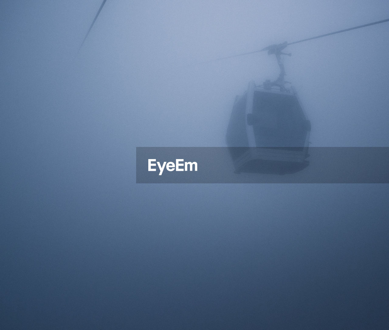 Low angle view of overhead cable car during foggy weather