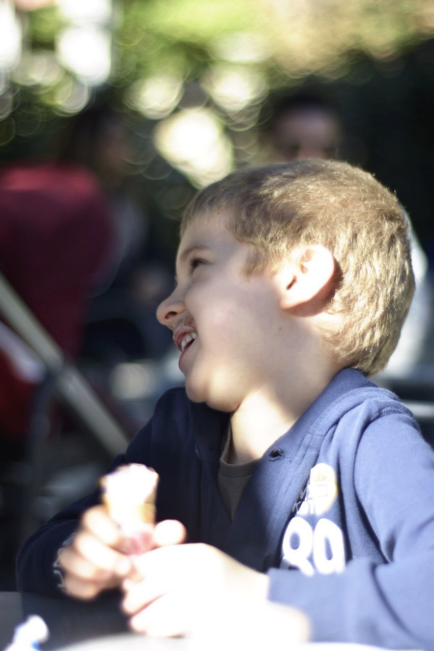 Happy boy looking away while holding ice cream by table