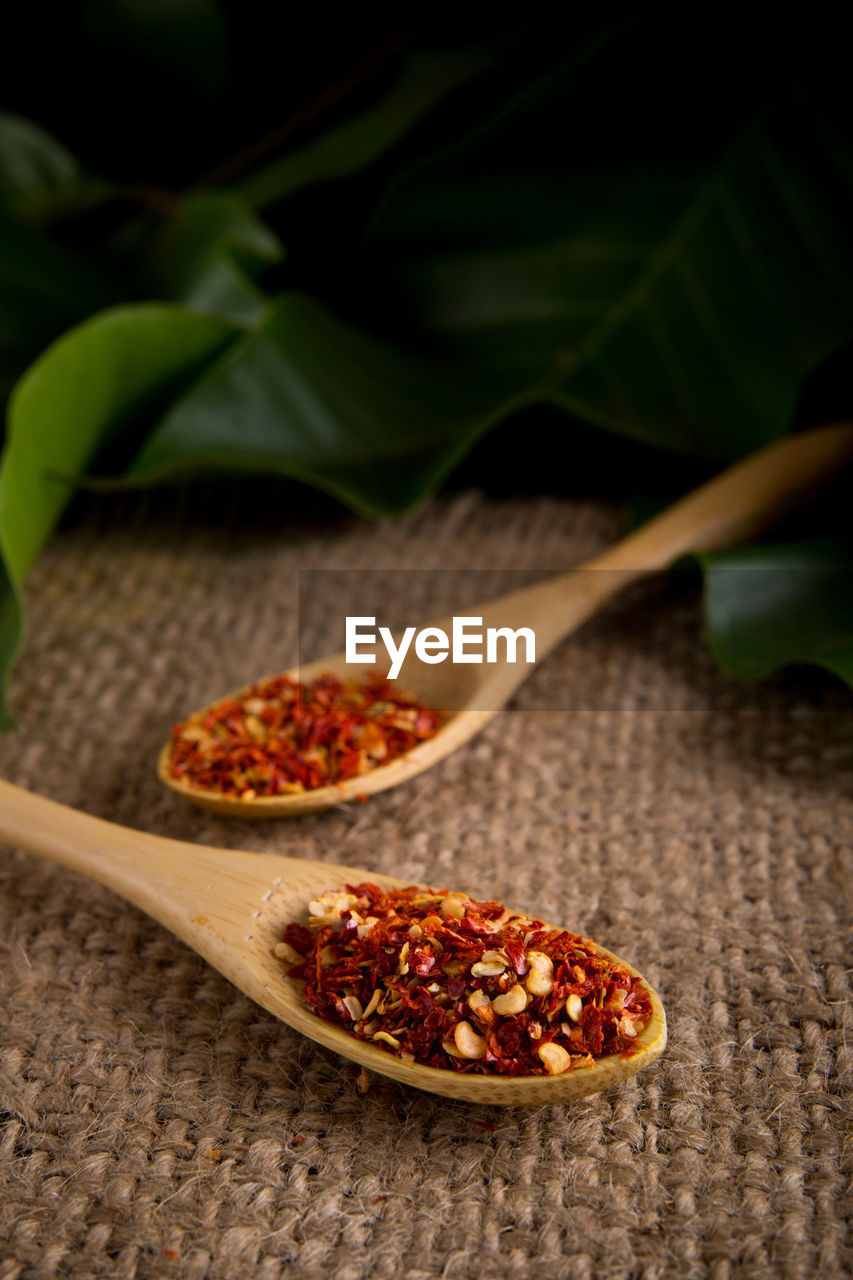 High angle view of dried chili in wooden spoons on burlap