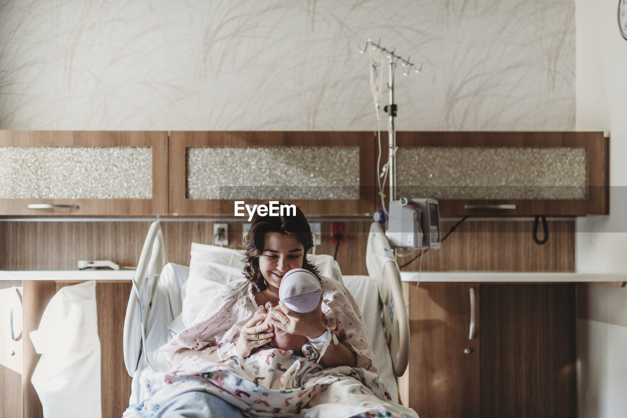 Mid view of mother in hospital bed looking at newborn son