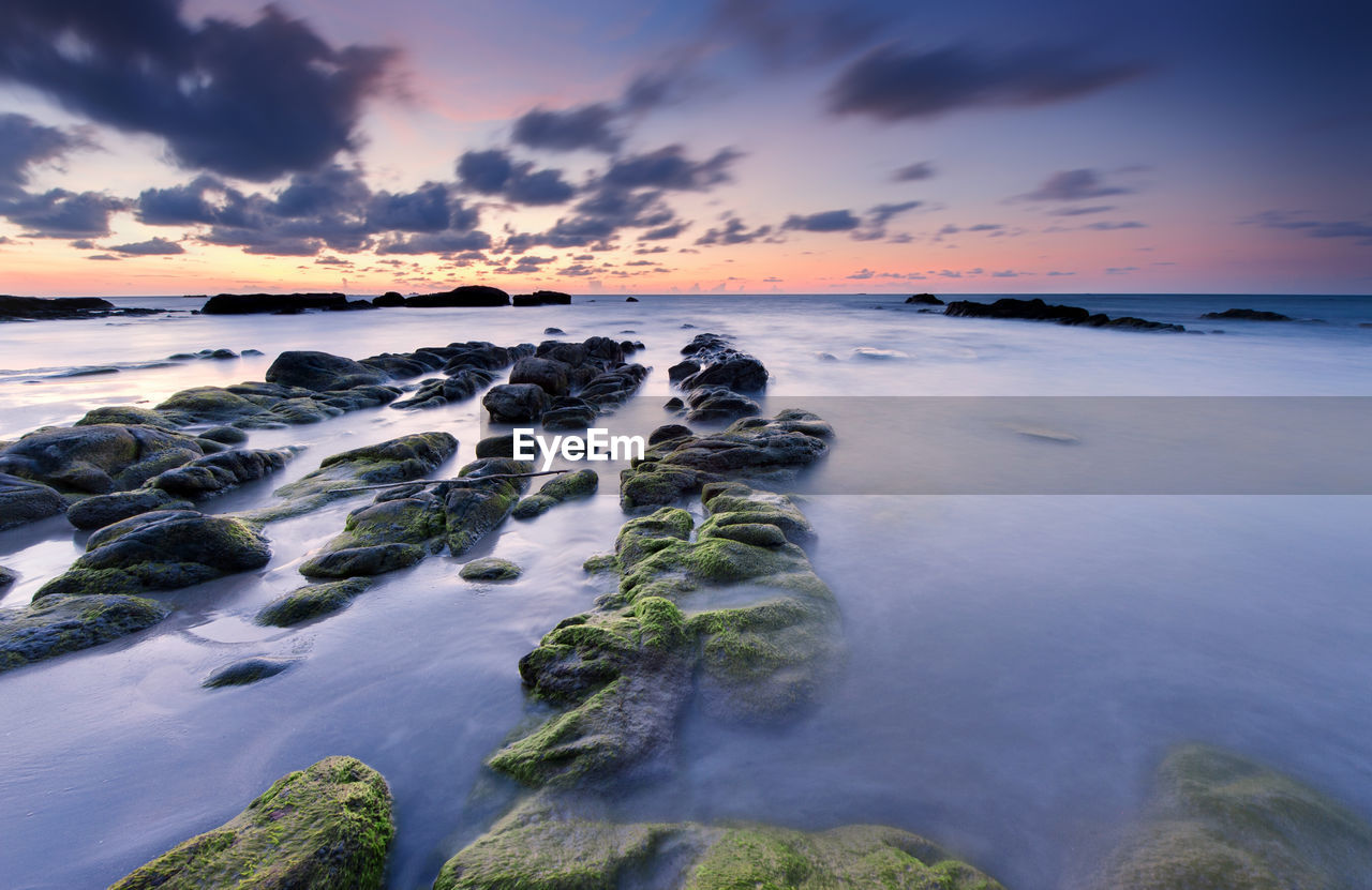 Scenic view of sea against dramatic sky during sunset