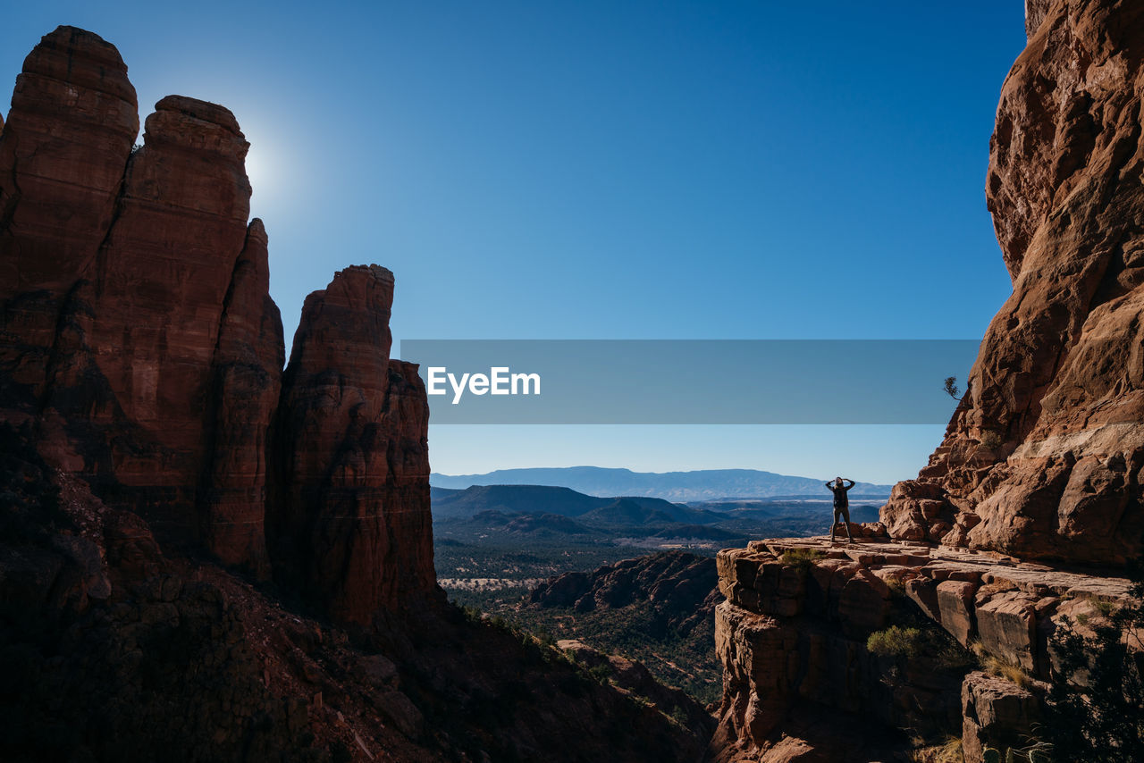 Silhouette woman standing on mountain against clear blue sky