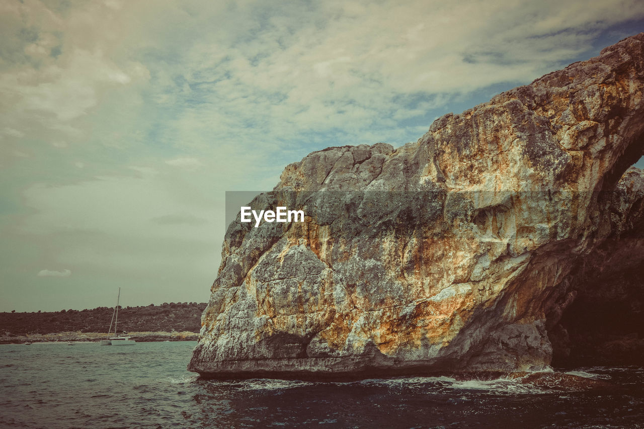 Rock formations by sea against sky