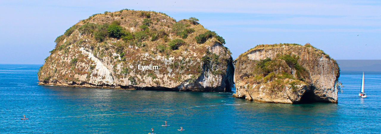 Rock formation in sea against blue sky