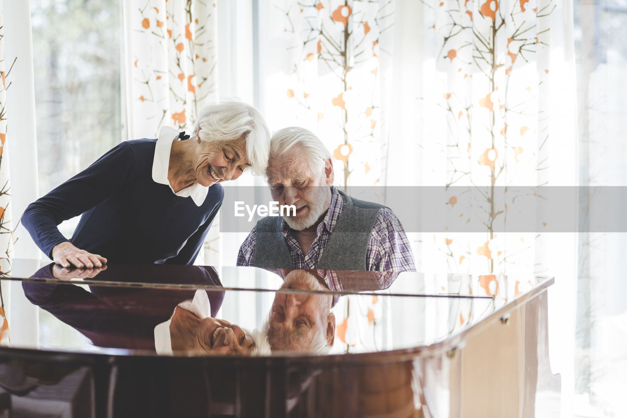 Senior couple playing piano together in nursing home