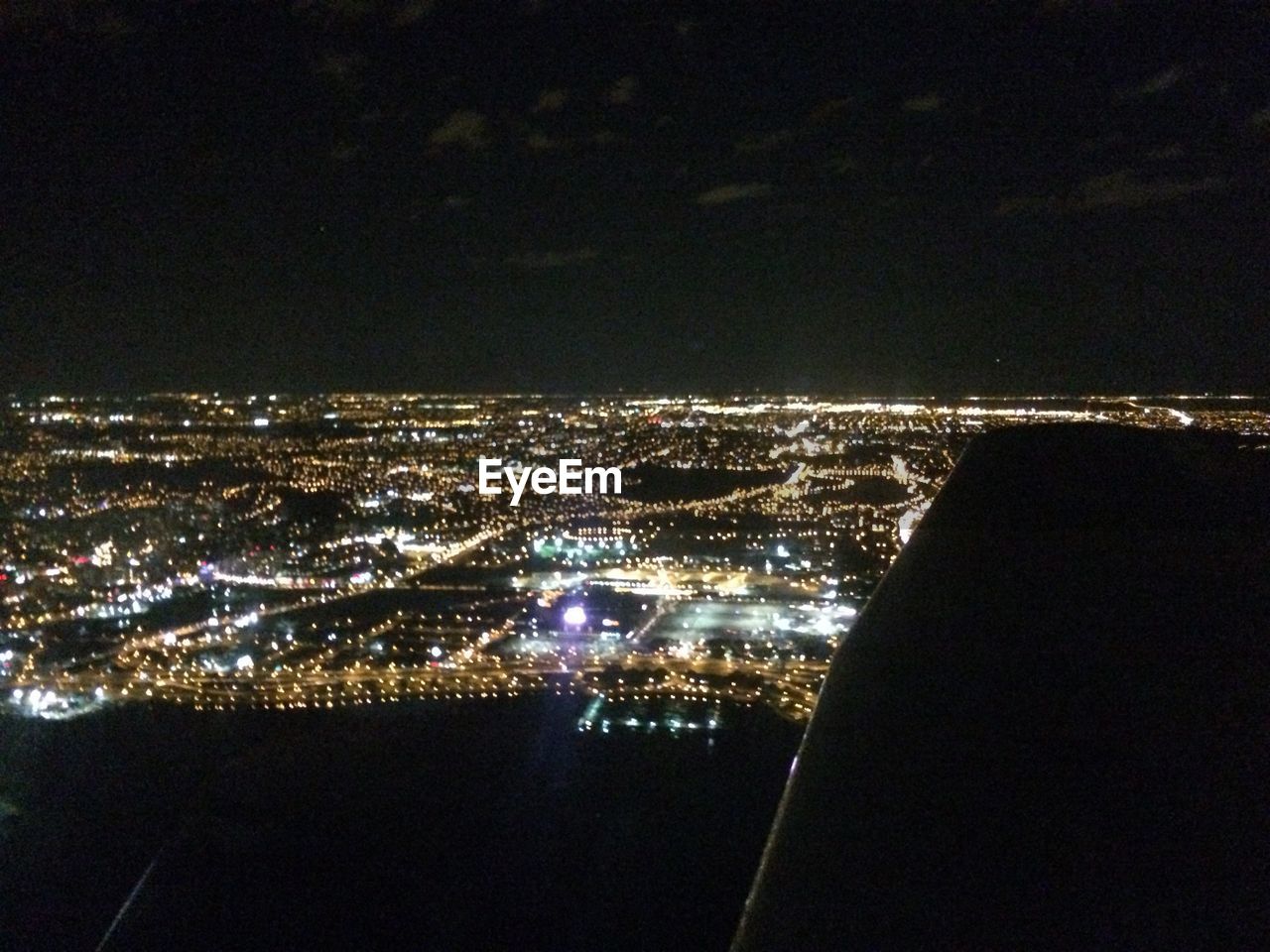 Cropped image of airplane flying over illuminated city