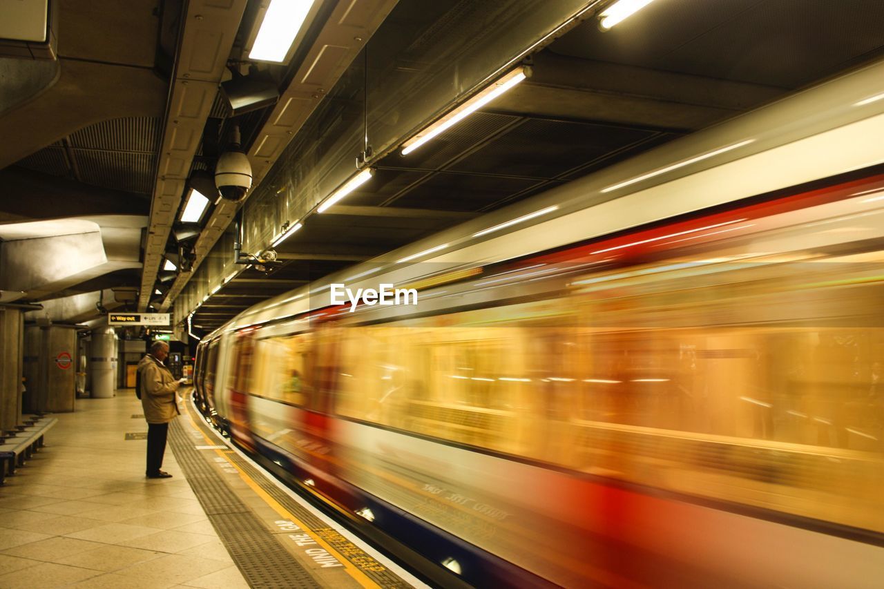 BLURRED MOTION OF TRAIN AT RAILROAD STATION PLATFORM