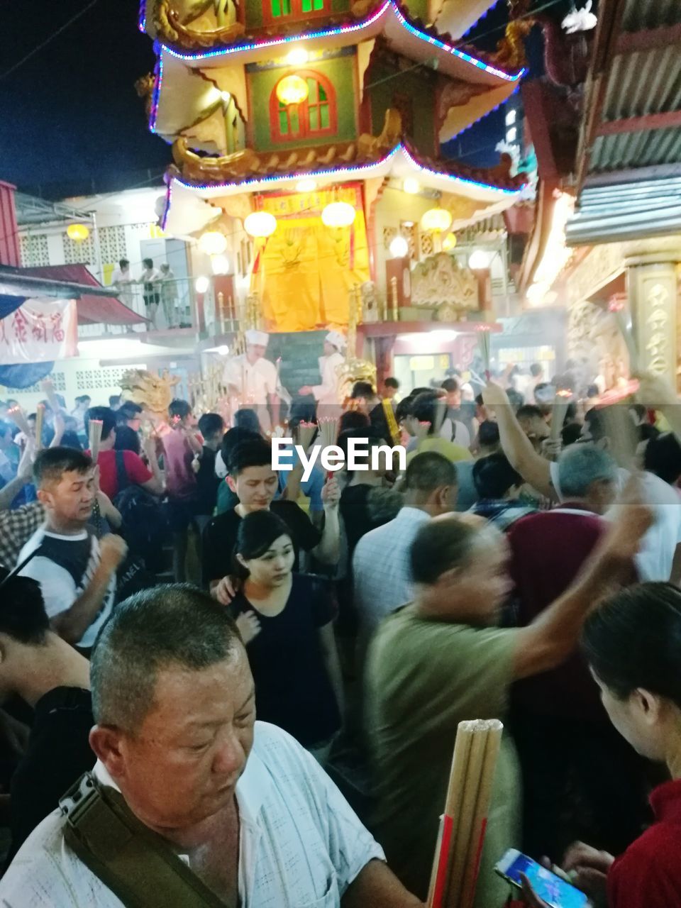 PEOPLE STANDING IN FRONT OF ILLUMINATED STREET