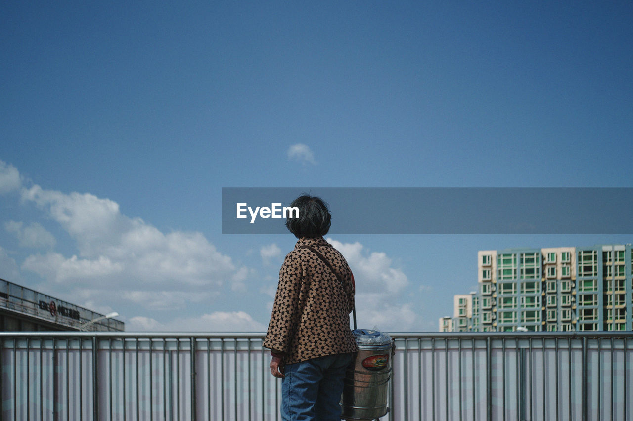 REAR VIEW OF A MAN AGAINST BUILDINGS