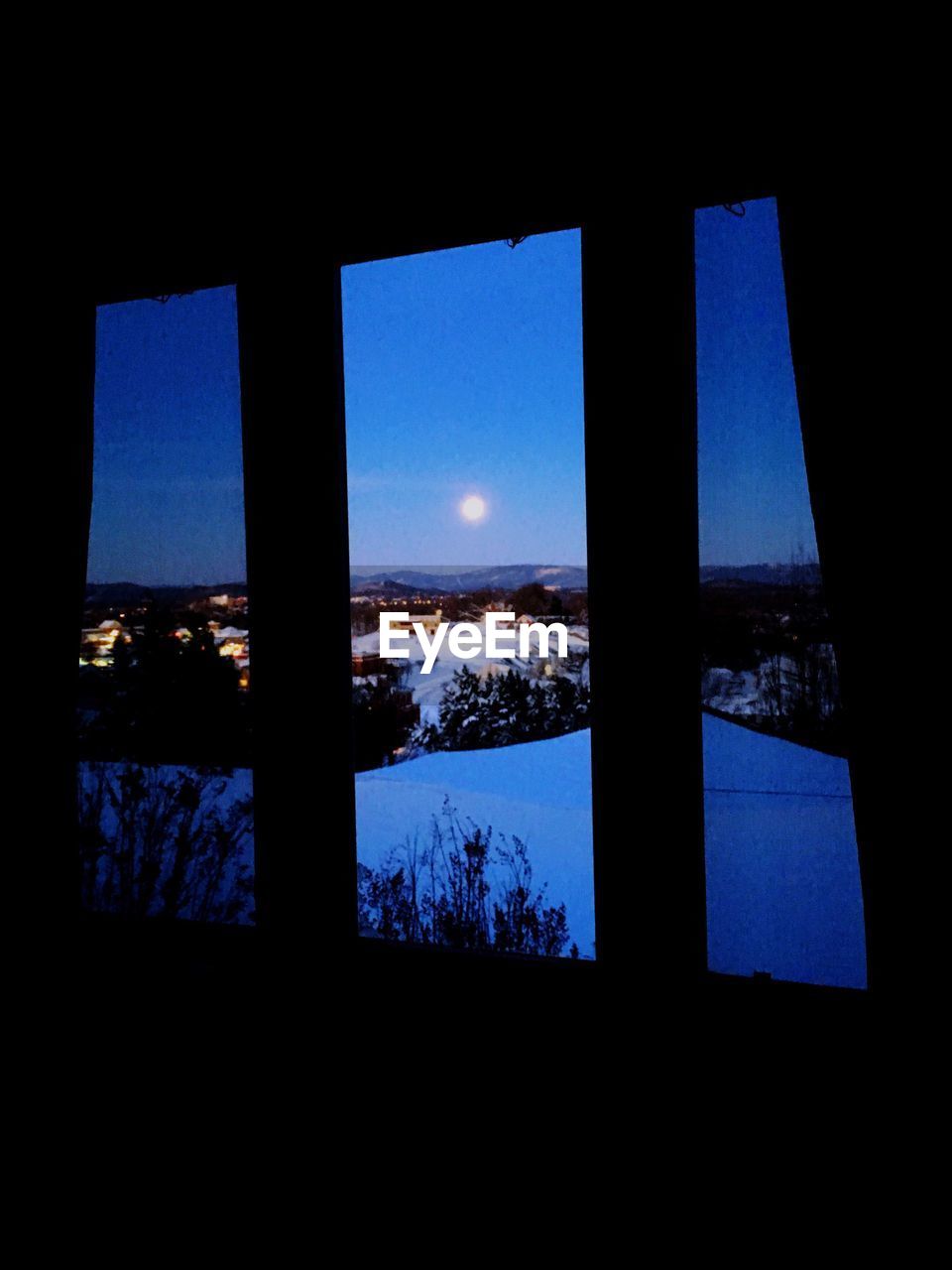 Full moon glowing over landscape at night seen from window