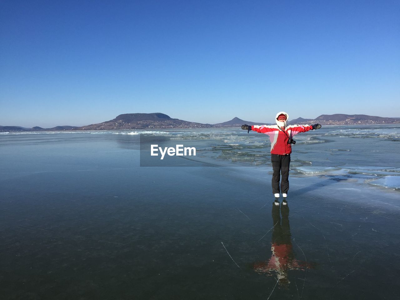Person with arms outstretched standing on frozen lake