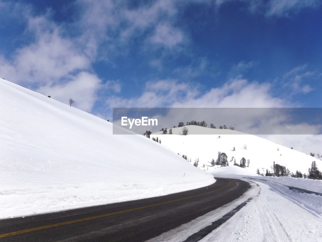 ROAD AMIDST SNOW COVERED MOUNTAINS AGAINST SKY