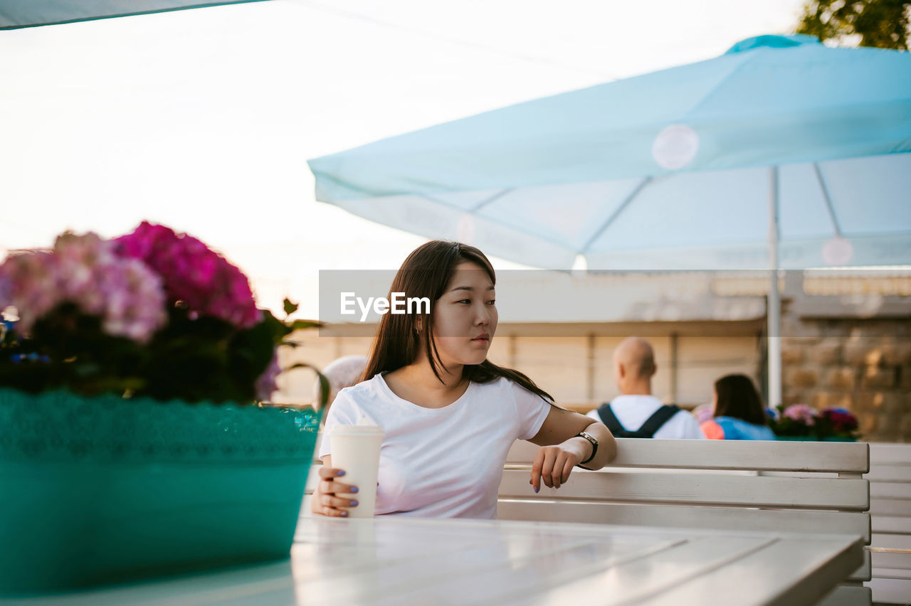 Thoughtful woman having drink while sitting in restaurant