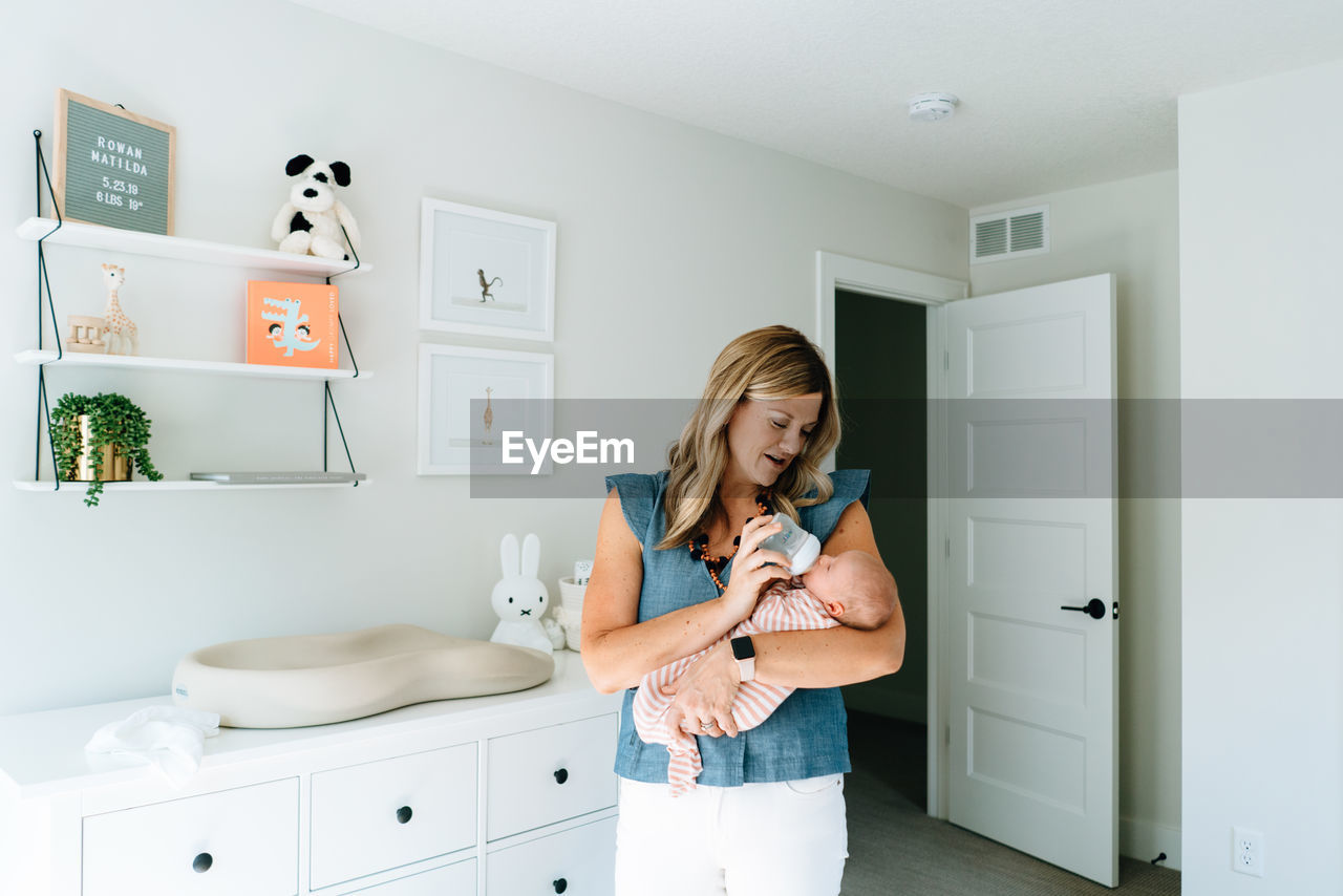 Straight on portrait of a new mom bottle feeding her baby girl